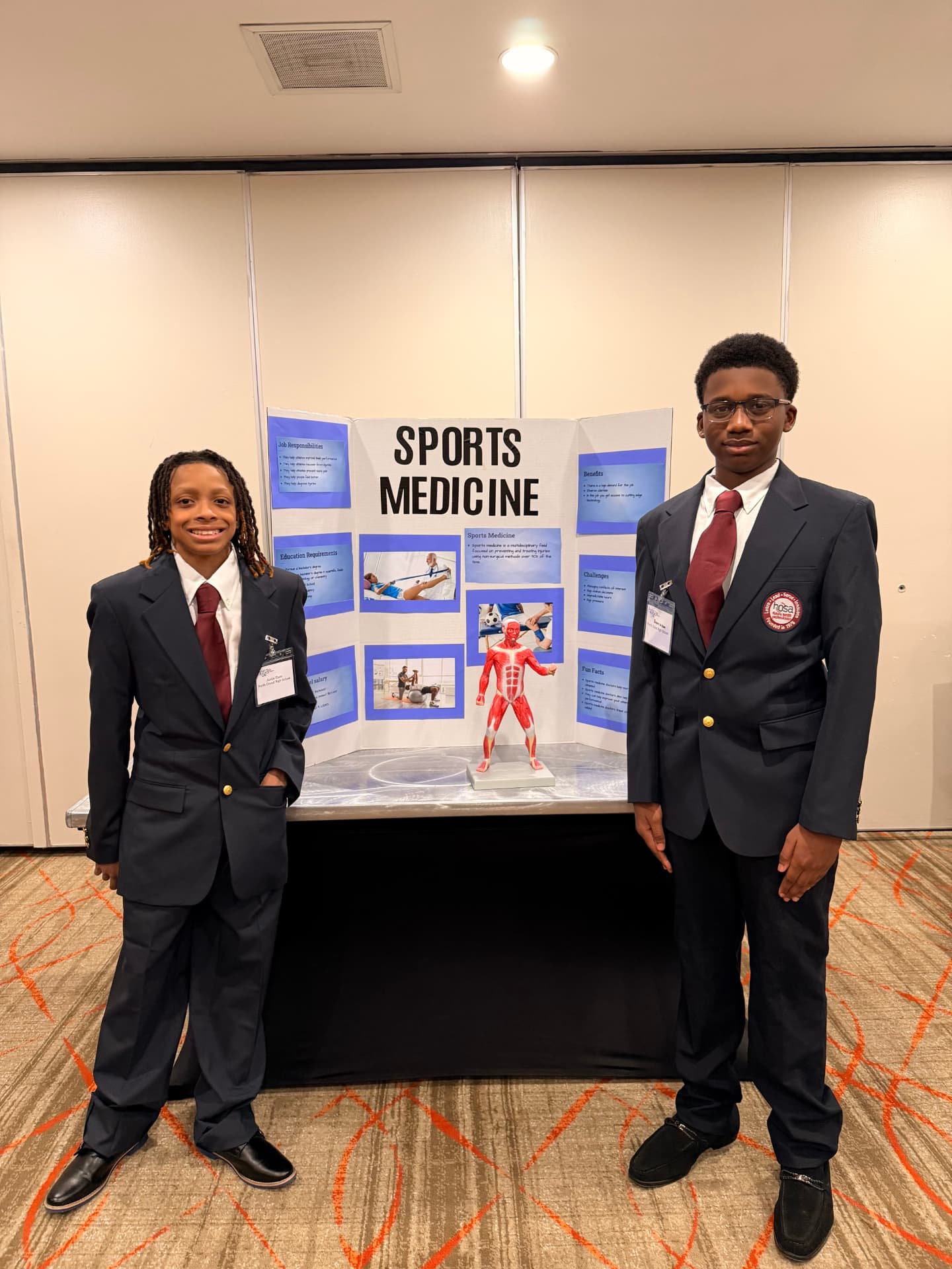 Two members present a Sports Medicine display board at a competitive event